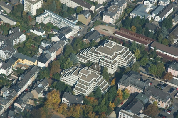 Luftaufnahme eines Wohngebiets mit mehreren mehrstöckigen Gebäuden, Straßen und Bäumen.