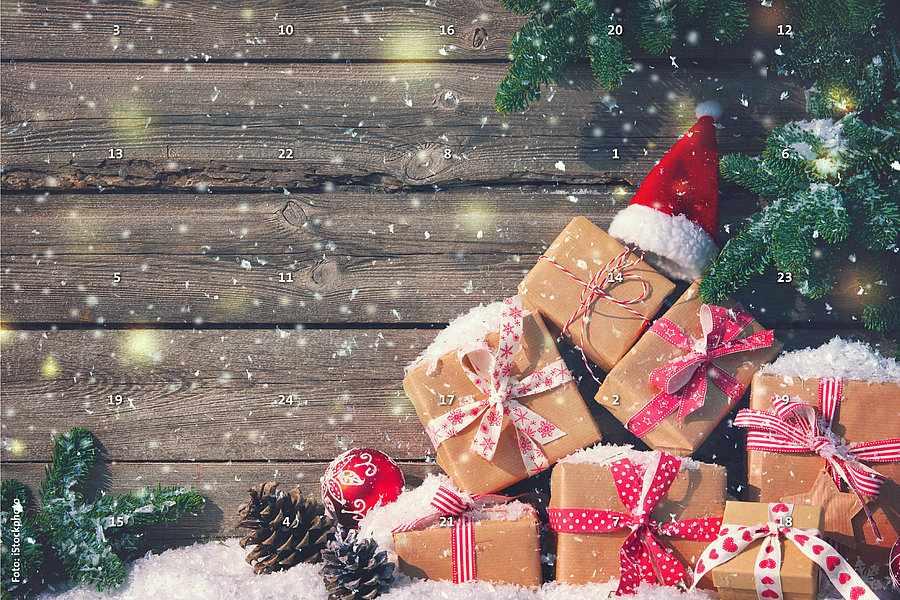 Mehrere mit Schleifen verzierte Geschenke liegen auf Schnee vor einer Holzplanke, daneben Tannenzweige, Zapfen und eine Weihnachtsmütze, es schneit leicht.