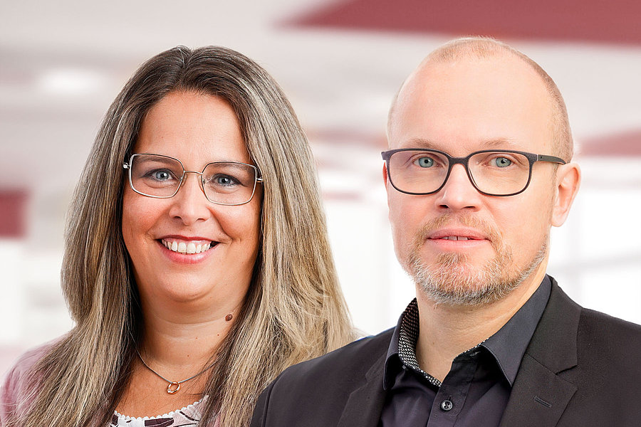 Anke Klauck mit langen braunblonden Haaren und Christian Link mit Brille und kurzem Haar, beide in Businesskleidung vor hellem Hintergrund