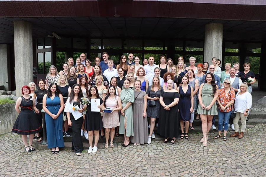 Große Gruppe von etwa 50 Personen, überwiegend Frauen, in sommerlicher Kleidung, posieren vor einem Gebäude mit Säulen und großen Fenstern