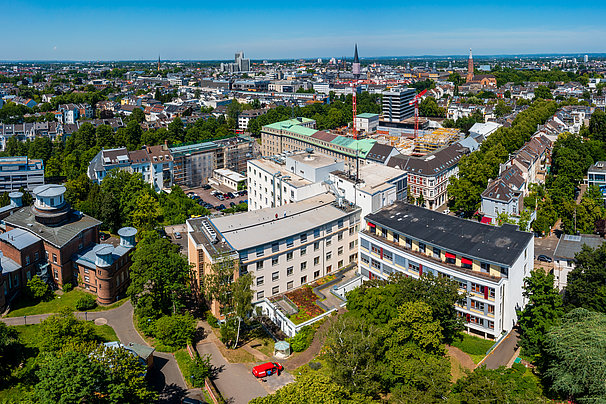 Luftaufnahme einer Stadt mit mehreren mehrstöckigen Gebäuden, Bäumen und Straßen unter klarem Himmel