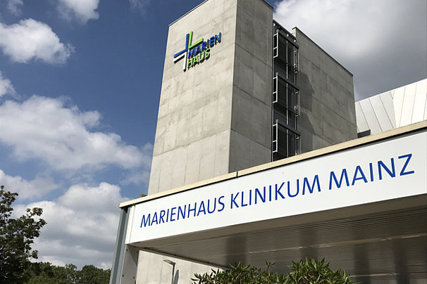 Eingang des Marienhaus Klinikums Mainz mit sichtbarem Gebäudeturm und blauem Himmel mit Wolken