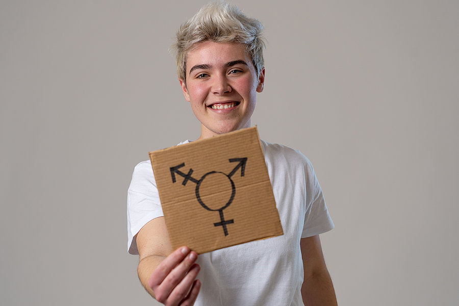 Person hält ein Pappschild mit einem Transgender-Symbol in die Kamera