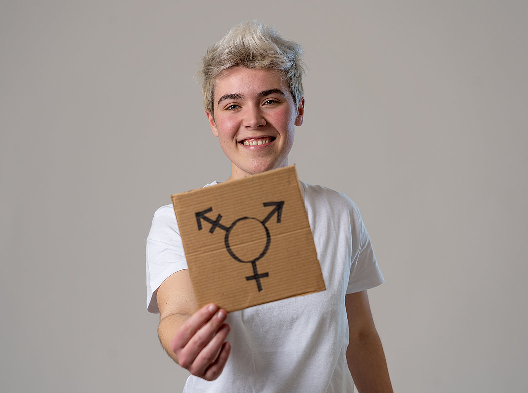 Person hält ein Pappschild mit einem Transgender-Symbol in die Kamera