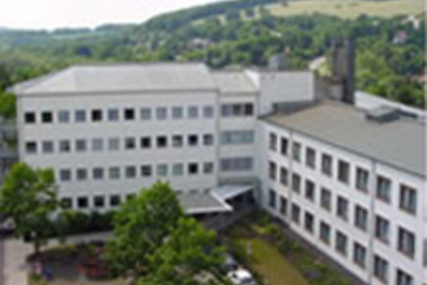 Mehrstöckiges Bürogebäude mit weißer Fassade und umliegenden Bäumen in einer hügeligen Landschaft