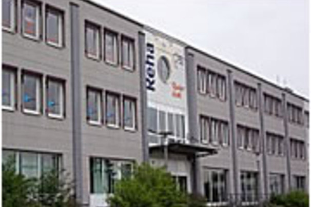 Mehrstöckiges Bürogebäude mit mehreren Fenstern und einem großen Banner mit dem Schriftzug 'Kohls' an der Fassade.