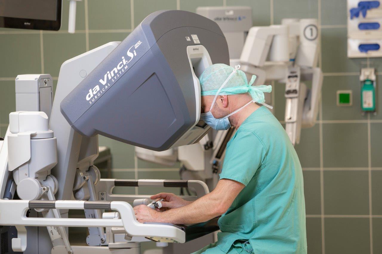Chirurg in OP-Kleidung bedient da Vinci Si Operationsroboter in einem Operationssaal