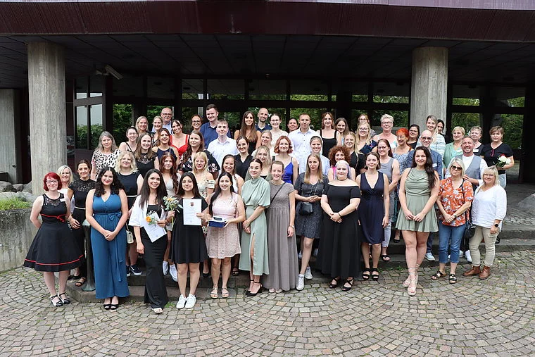 Große Gruppe von etwa 50 Personen, überwiegend Frauen, in sommerlicher Kleidung, posieren vor einem Gebäude mit Säulen und großen Fenstern